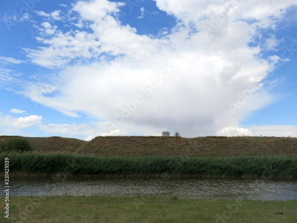 Obraz Blue sky with clouds over a river.