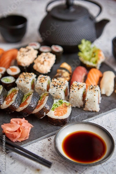 Fototapeta Assortment of different kinds of sushi rolls placed on black stone board