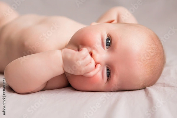 Fototapeta Happy 3 months old baby smiling, lying on white bed
