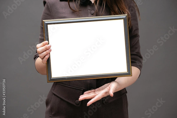 Fototapeta Blank diploma certificate mockup. Woman with empty photo frame with copy space close up.