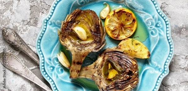 Fototapeta artichoke grill. Tasty vegetables are first cooked for a couple, then fried on a grill, poured with olive oil and spices. background concrete. top view.  copy space. 