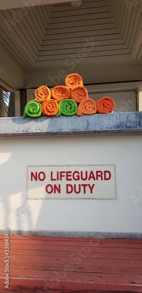 Obraz Closeup of colorful towels and no lifeguard on duty warning sign at swimming pool.  Safety concept..