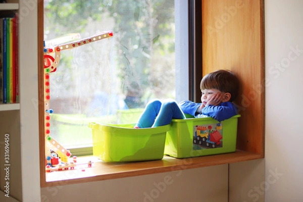 Obraz Czteroletni chłopiec siedzi znudzony w swoim pokoju 18 marca 2020 roku.