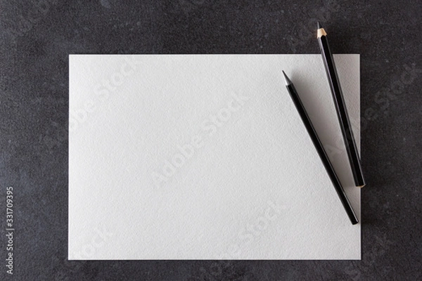 Obraz Paper mockup. Watercolor A4 paper with black pencils on dark background.