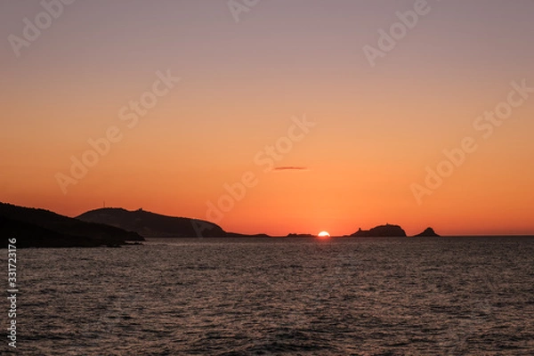 Fototapeta Sun setting behind La Pietra at Ile Rousse in Corsica