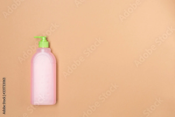 Fototapeta Plastic bootle of liquid soap shampoo with dispenser, closeup, isolated in beige background. Free space. Washing hands