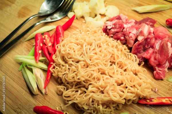 Fototapeta Instant noodles with pork, pepper and lemon grass in a bowl, Asian meal on a table