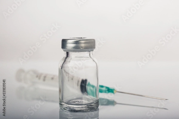 Fototapeta Empty medical vial with syringe and needle on white background.Dramatic color tone