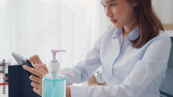 Fototapeta Selective focus of alcohol gel bottle on table, woman working in blur background prepared sanitizer gel for hand wash to clean germ, bacteria and virus. Pandemic protection and Health care concept.