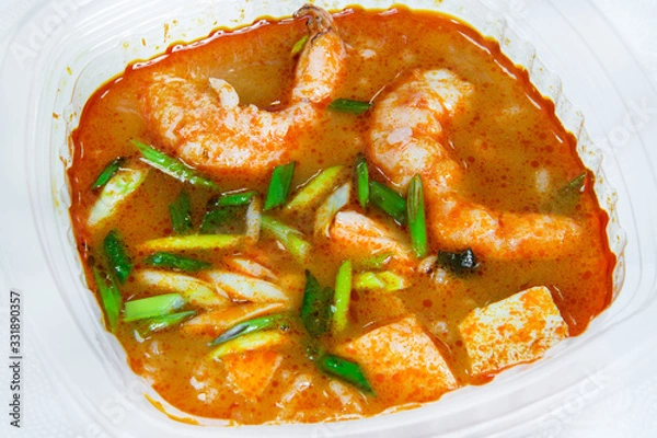 Fototapeta Tomato soup with king prawns and fish with onion feathers