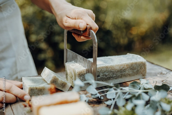 Fototapeta Woman is making handmade natural soaps on an old wooden table