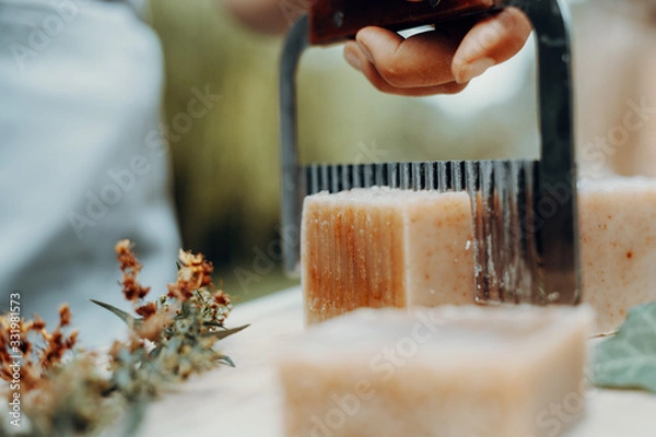 Fototapeta Woman is making handmade natural soaps on an old wooden table