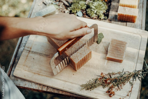 Fototapeta Woman is making handmade natural soaps on an old wooden table