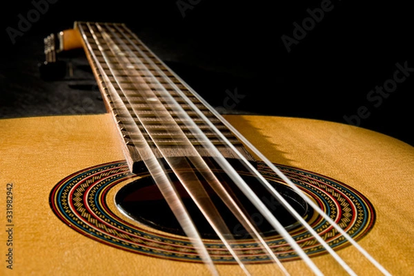 Obraz Gitara klasyczna z wibrującymi strunami na czarnym tle