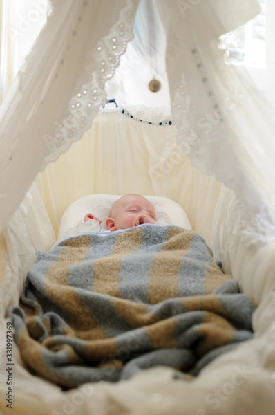 Fototapeta newborn baby firs day at home, asleep into the warmth, peace and tranquillity of the cot