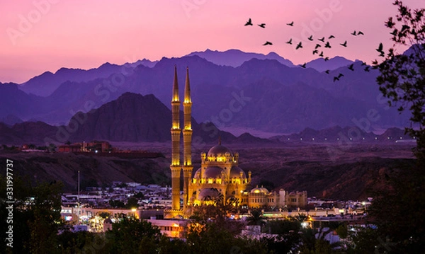 Fototapeta Al-Sahaba Mosque with night lights - arabic architecture and monuments in Sharm el Sheikh, Egypt. Ancient mosque of the old town at sunset with mountains silhouettes on skyline.