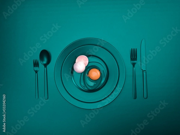 Fototapeta Turquoise dishes with a broken egg and shell on a plate. Ceramic dishes with a fork, spoon and knife. For cafes, posters, breakfasts and dinners. Copyspace for your individual text