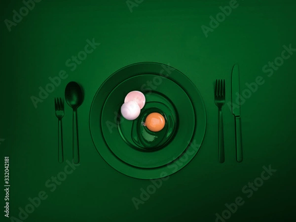 Fototapeta Green dishes with a broken egg and shell on a plate. Ceramic dishes with a fork, spoon and knife. For cafes, posters, breakfasts and dinners. Copyspace for your individual text