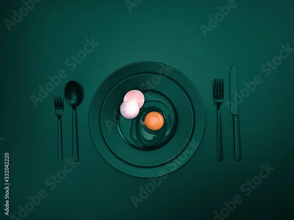 Fototapeta Emerald dishes with a broken egg and shell on a plate. Ceramic dishes with a fork, spoon and knife. For cafes, posters, breakfasts and dinners. Copyspace for your individual text