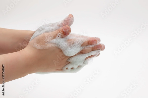 Fototapeta Hands of child on a white background in white foam from antibacterial soap