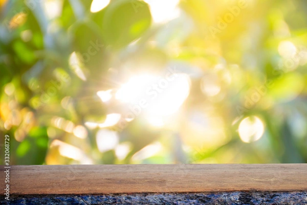 Fototapeta Display the product on a wooden table. The bokeh background from the sun is passing through the leaves