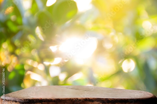 Fototapeta Display the product on a wooden table. The bokeh background from the sun is passing through the leaves