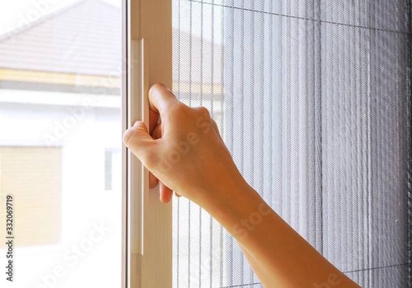 Fototapeta Woman hand hold retractable pleated insect screen holder to open or close the window ,selective focus on the hand