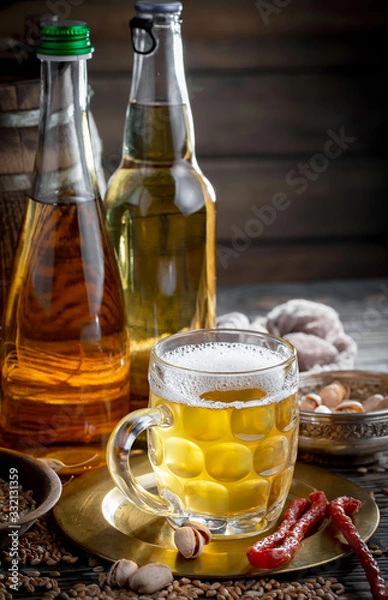 Fototapeta Light frothing beer in a glass, on an old background.