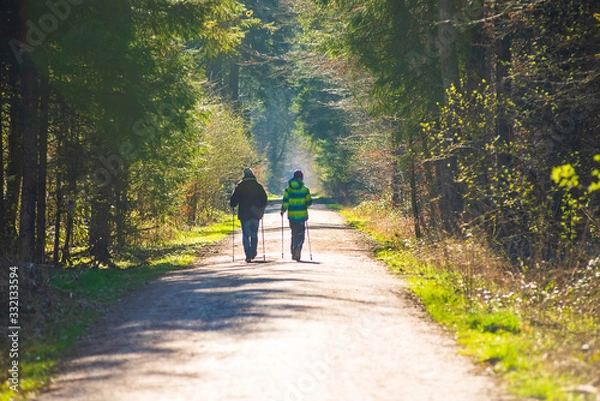 Fototapeta A mother and her son  do nordic walking on a forest path during the corona virus lockdown in germany, with families and single persons allowed to go out on strolls.