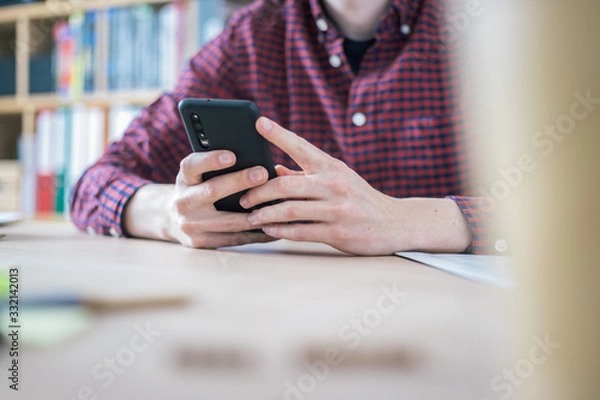 Fototapeta Home office concept: Man is typing on his black mobile phone
