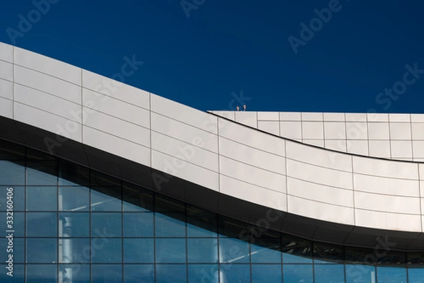 Obraz A fragment of the roof of a modern building with curved lines with a blue sky background