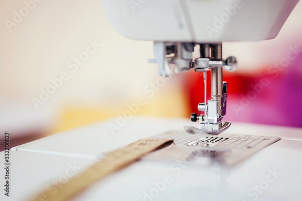 Obraz Presser foot with needle on a sewing machine with blurred background