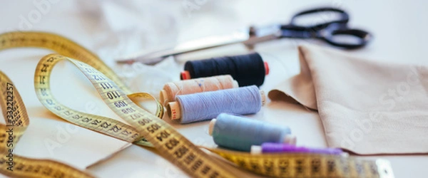 Obraz Composition of seamstress threads and scissors on a white table. Concept of a clothing designer