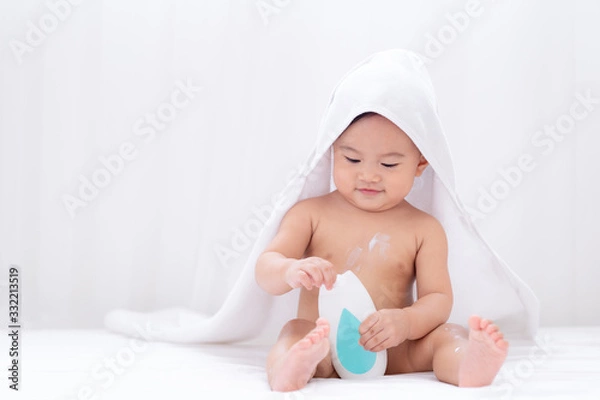 Fototapeta Asian cute baby wearing white towel after taking a shower applying moisturizing cream baby lotion,Childhood baby health  care and skin care concept.