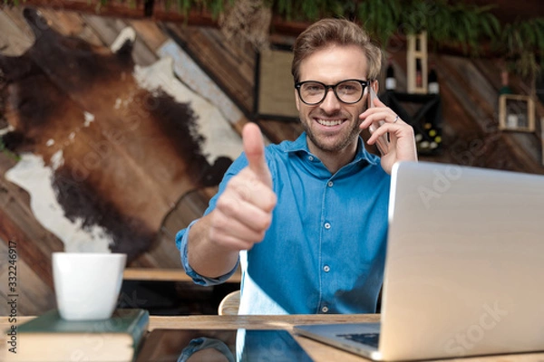 Fototapeta businessman talking on phone while giving a thumbs up