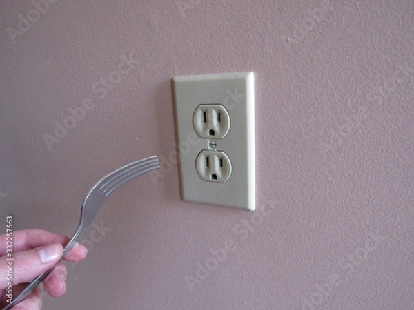 Obraz A person putting a fork into an electrical outlet 