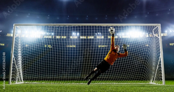 Obraz Goalkeeper is trying to save from a goal on an empty soccer stadium. No spectators on the tribunes. Stadium is made in 3d.