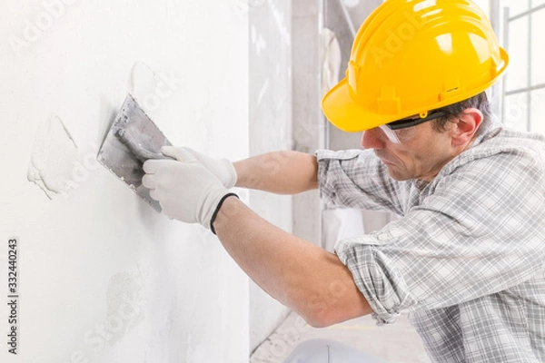 Fototapeta Plasterer using finishing trowel to smooth a wall
