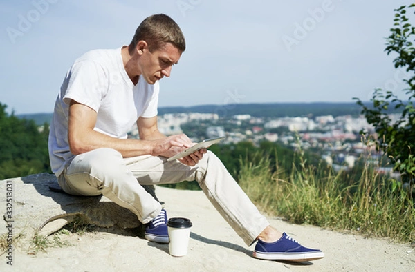 Fototapeta man holding digital tablet outdoors while he is working