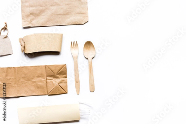 Fototapeta food delivery with paper bags and flatware on gray table background top view mockup