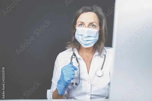 Fototapeta Eine Frau, Ärztin mit Stethoskop sitzt vor dem Laptop. Homeoffice in der Medizin? 