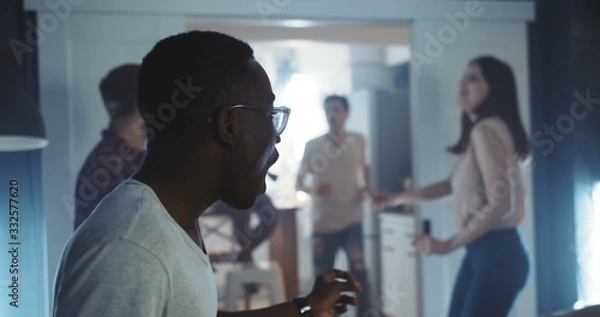Fototapeta Happy young smiling African man dancing with friends at multiethnic party, celebrating holidays together slow motion.