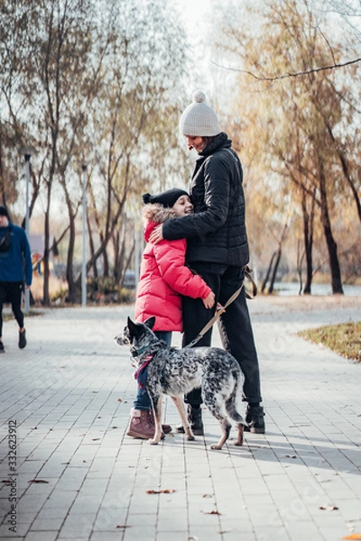 Fototapeta Happy mother and her daughter walk with dog in autumn park