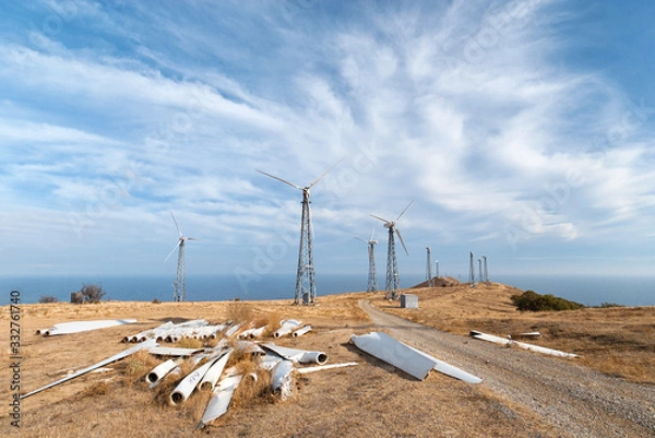 Obraz Dilapidated wind power station with spare parts of wind turbines in the foreground