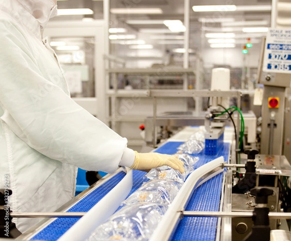 Obraz Assembly line medical tech worker making IV bags. 