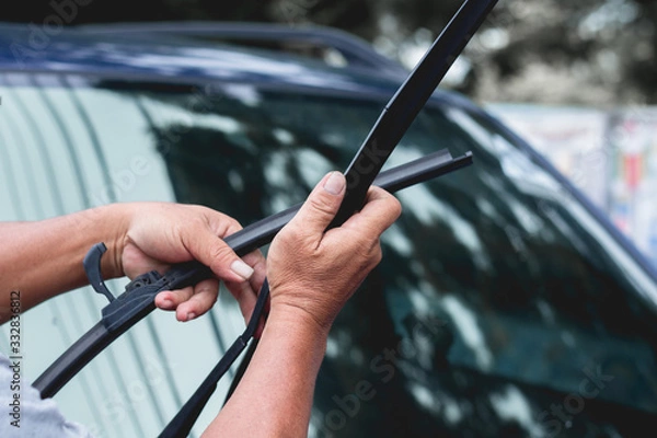 Fototapeta Mechanic replace windshield wipers on car. Replacing wiper blades
