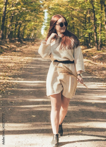 Fototapeta  Stylish girl in glasses and a hat walks along a forest path