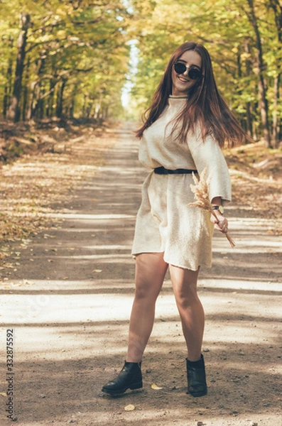 Fototapeta  Stylish girl in glasses and a hat walks along a forest path