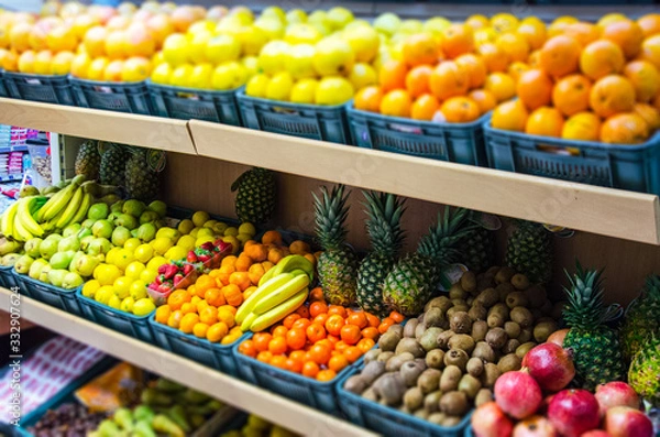 Fototapeta Fruit on a shelf in the market. Bananas, oranges, lemons, strawberries, apples, pineapples, kiwi are presented.