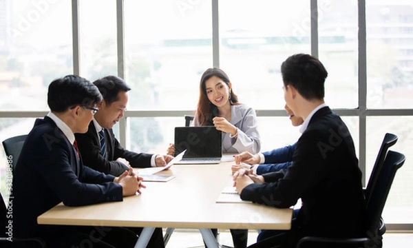 Fototapeta Business woman making a presentation at office. Business executive delivering a presentation to his colleagues during meeting or in-house business training, explaining business plans to his employees.